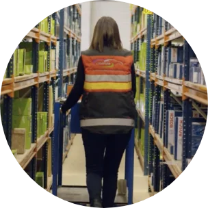 Magazijnmedewerker met veiligheidsvest tussen rekken vol auto-onderdelen van verschillende merken