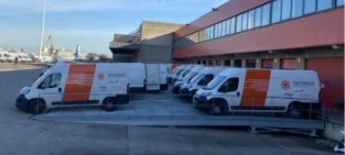 DISTRIGO-bestelwagens geparkeerd bij een magazijn, klaar voor de levering van auto-onderdelen.